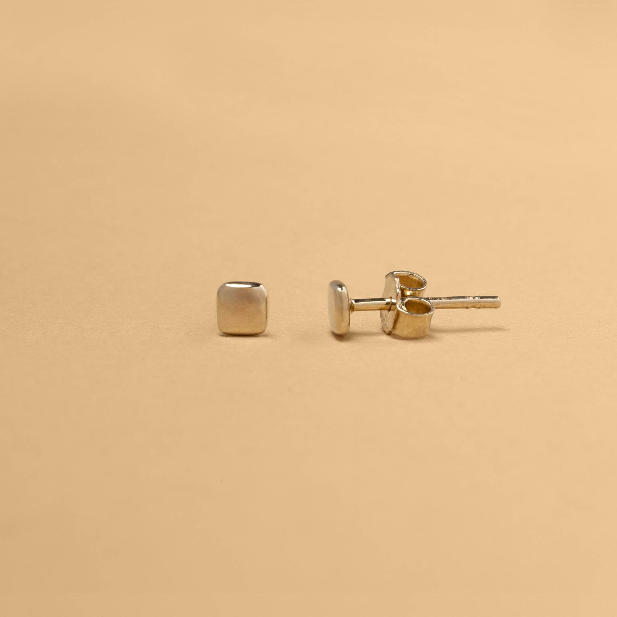 Kvadratiska stiftörhängen i 14K guld med stillsam, arkitektonisk form – ett smycke anpassat för vardagens rörelse.