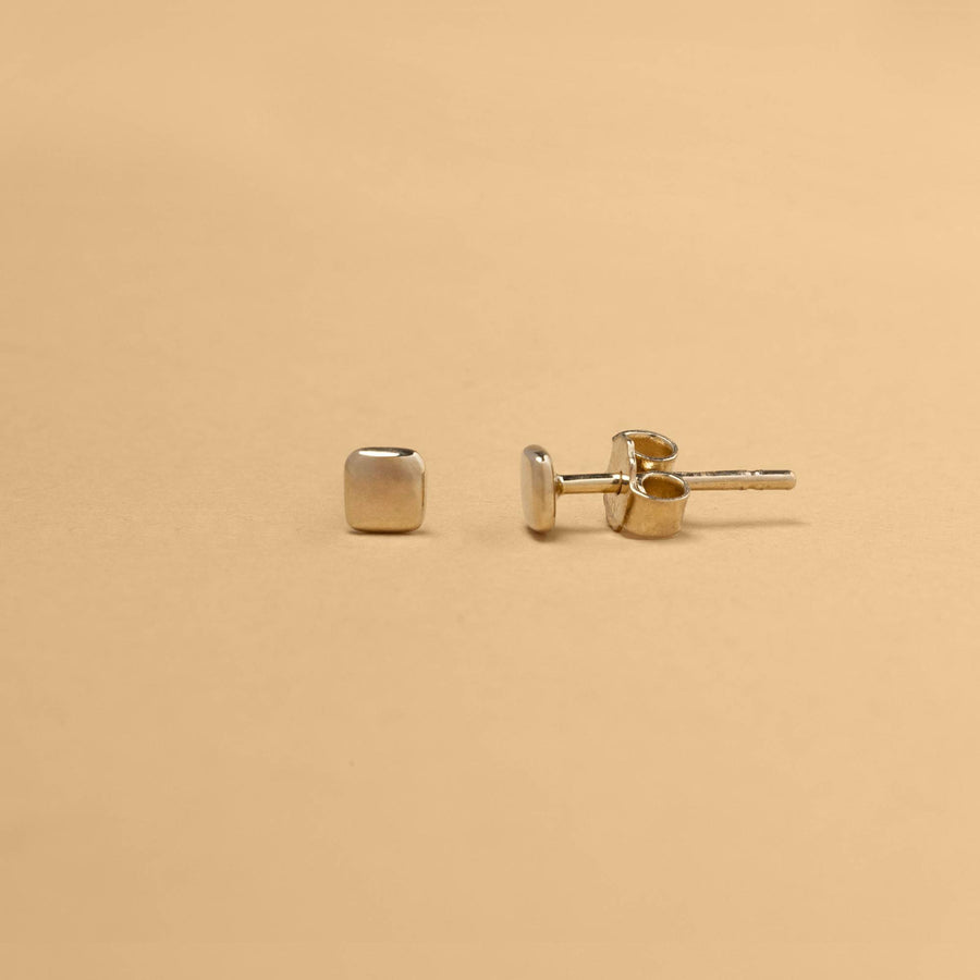 Kvadratiska stiftörhängen i 14K guld med stillsam, arkitektonisk form – ett smycke anpassat för vardagens rörelse.