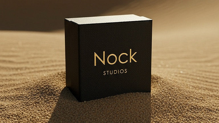 Elegant svart smyckesask från Nock Studios placerad i gyllene sand – en symbol för tyst lyx, skandinavisk minimalism och hållbar design i 14K guld.