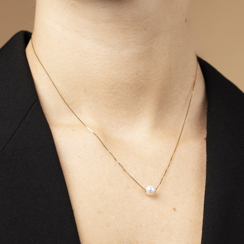 Närbild: Kvinna halsband i 14K guld med sötvattenspärla – bärs på modell. Elegant smycke för vardag och ceremoni. Perfekt present eller arvegods.

