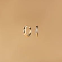 Arcus Hoops Örhängen i 14K guld – designade som mjuka bågar fotograferade mot beige bakgrund