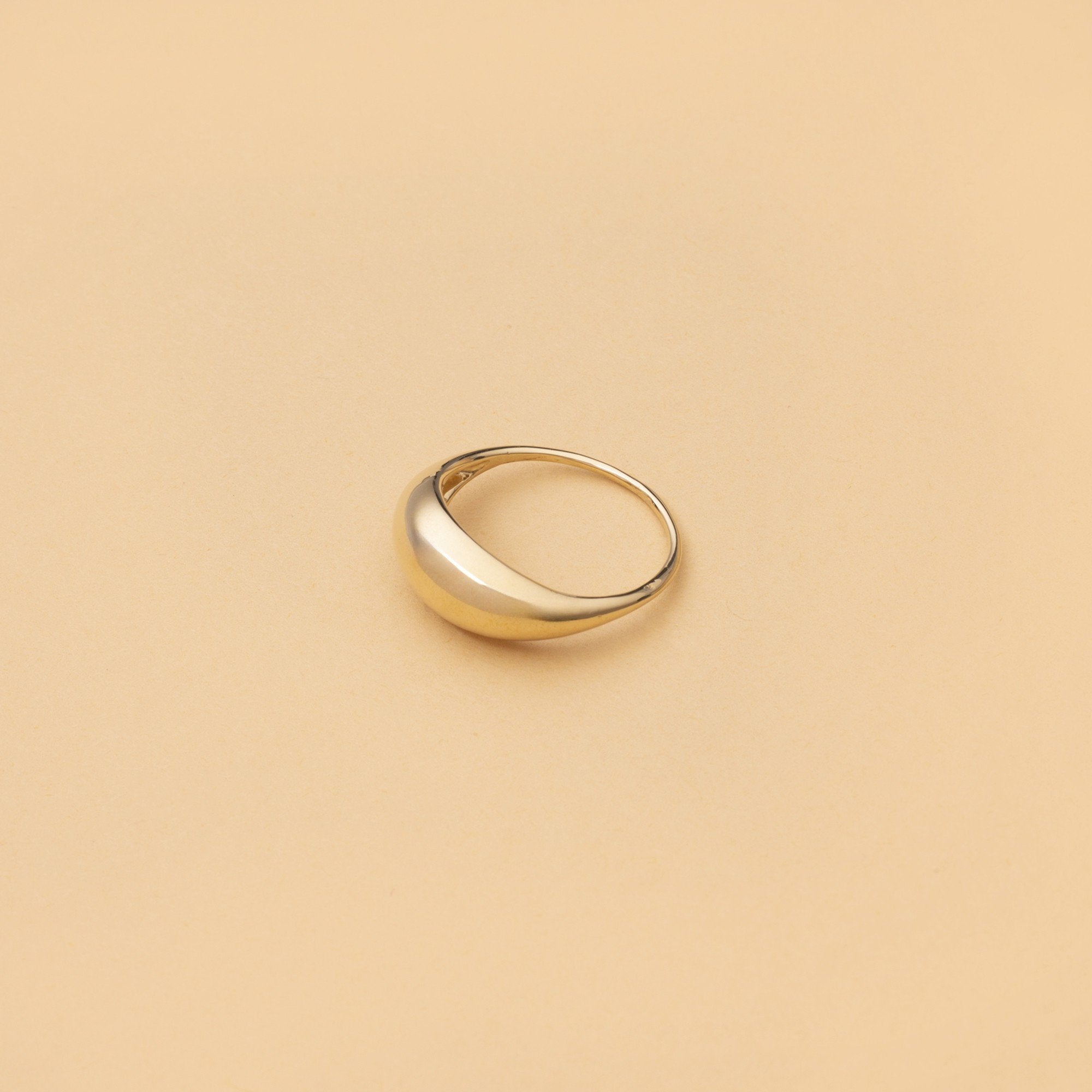 Arcus Ring i 14K guld – platt produktbild på beige bakgrund från Nock Studios.

