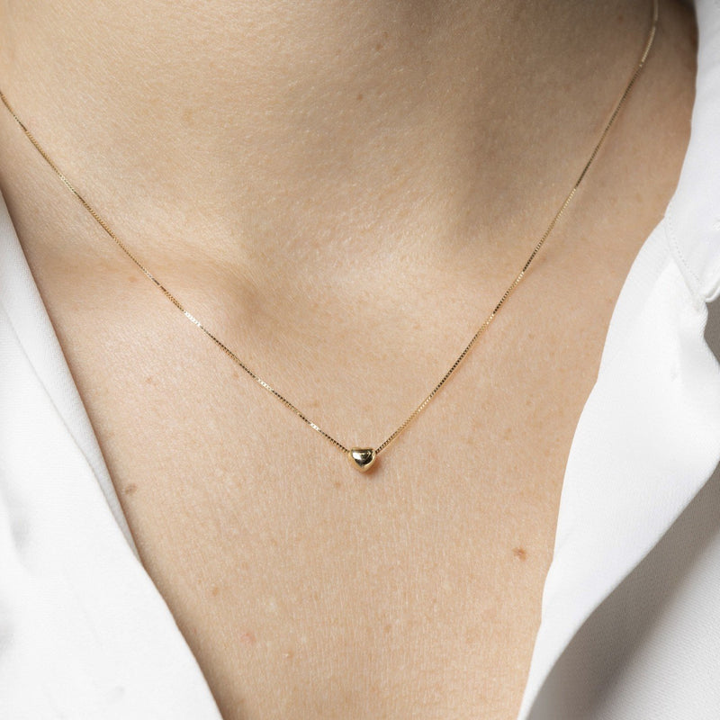 Innersta – Hjärtformat halsband i 14K guld bärs av modell, subtil och minimalistisk design från Nock Studios.