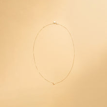 Innersta – hjärthalsband i 14K guld från Nock Studios, fotograferat på ljus bakgrund för att framhäva smyckets minimalistiska design och glans.