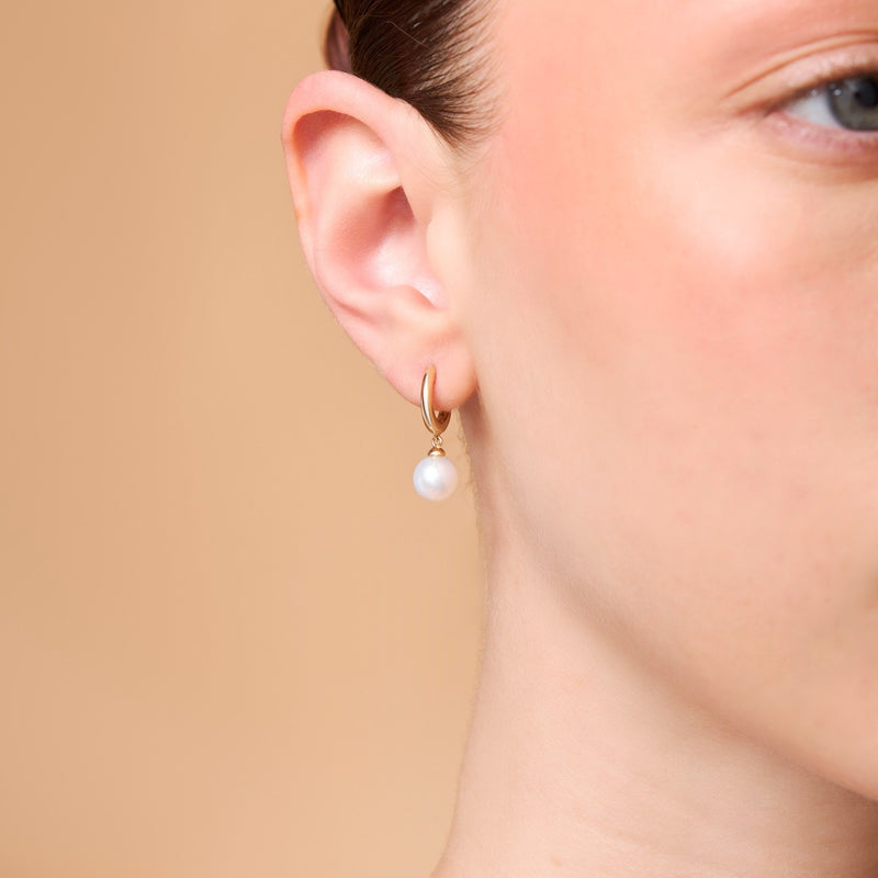 Kvinna bär pärlörhängen i 14K guld från Nock Studios – en hyllning till transformation och feminin styrka.