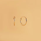 12 mm guldörhängen i 14K – Nock Hoops från Nock Studios. Minimalistisk design med flexrörsteknik för lätt, daglig bärkomfort.