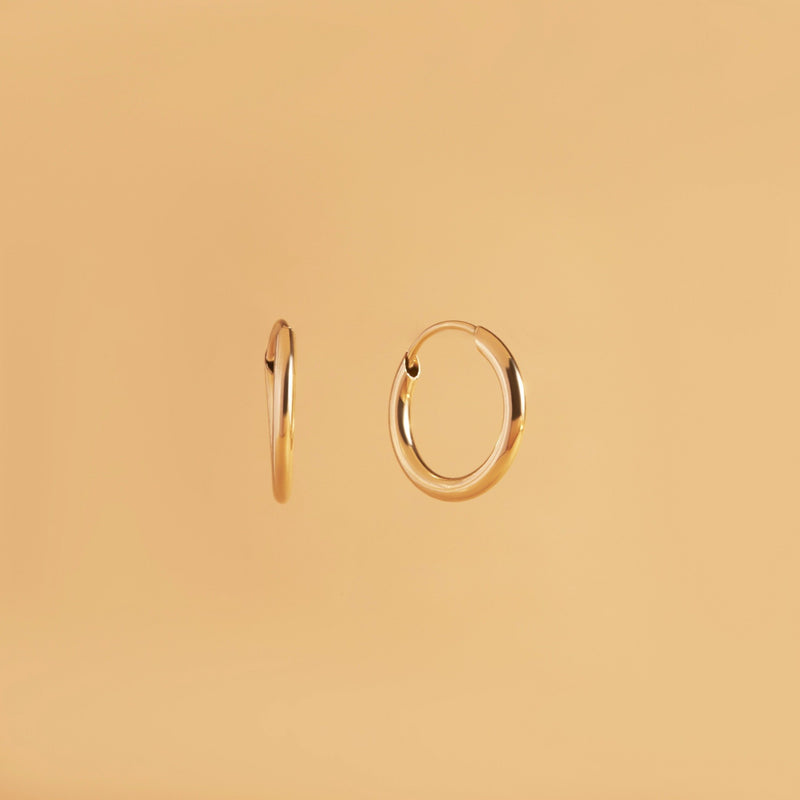 12 mm guldörhängen i 14K – Nock Hoops från Nock Studios. Minimalistisk design med flexrörsteknik för lätt, daglig bärkomfort.