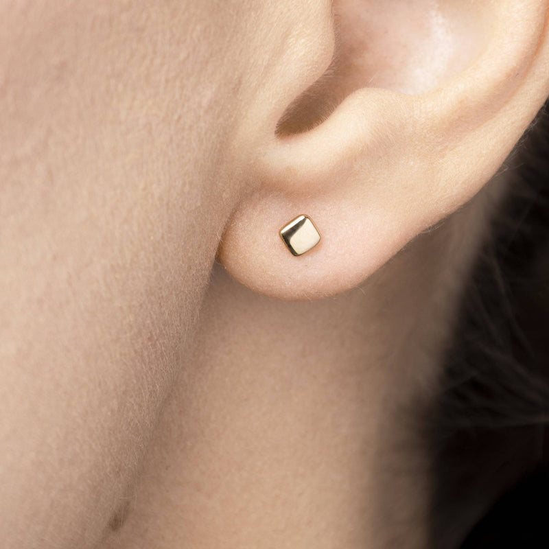 Stilren närbild på örhänget Tavla – kvadratisk design i 14K guld från Nock Studios.

