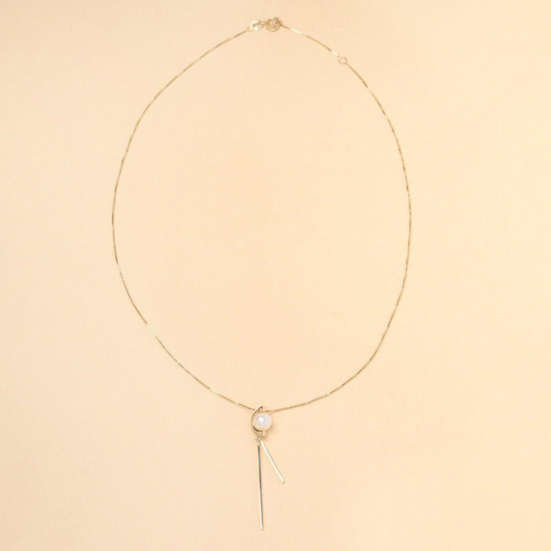Tick & Tack Halsband i 14K Guld – flatlay med pärla, halvcirkel och två hängande rektangulära linjer.