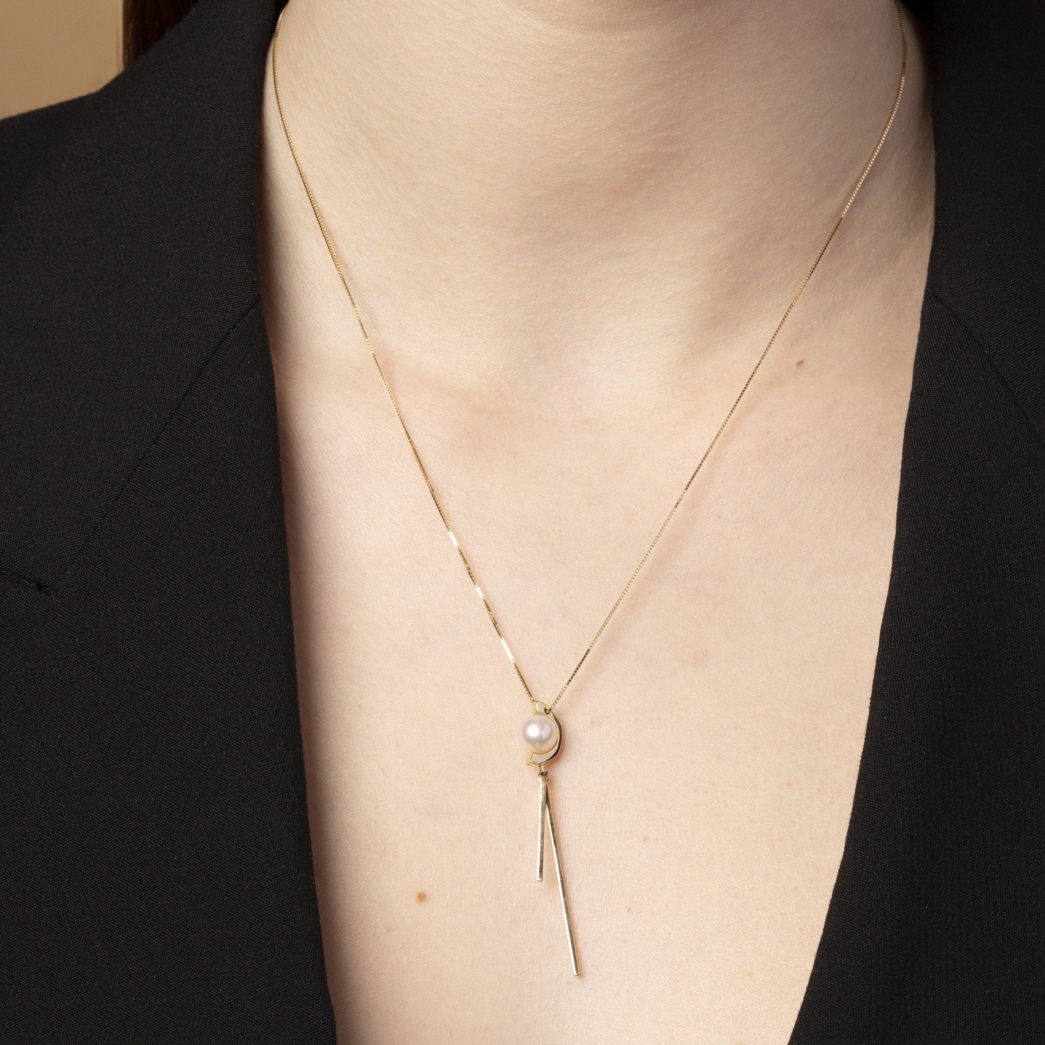Tick & Tack Halsband i 14K Guld – bärs av kvinna med svart kavaj, poetisk och rytmisk design.